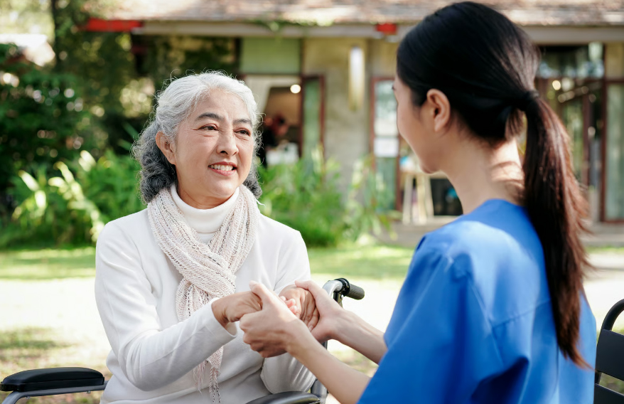 Close-up of a hospice nurse holding the hands of a smiling senior woman to provide comfort and reassurance.